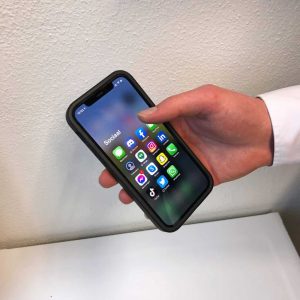 Een mobiel in iemands hand met allerlei apps - content kanalen - JKC Media