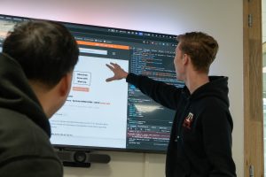 Een collega geeft uitleg aan een andere collega over een website via een tv-scherm - JKC Media